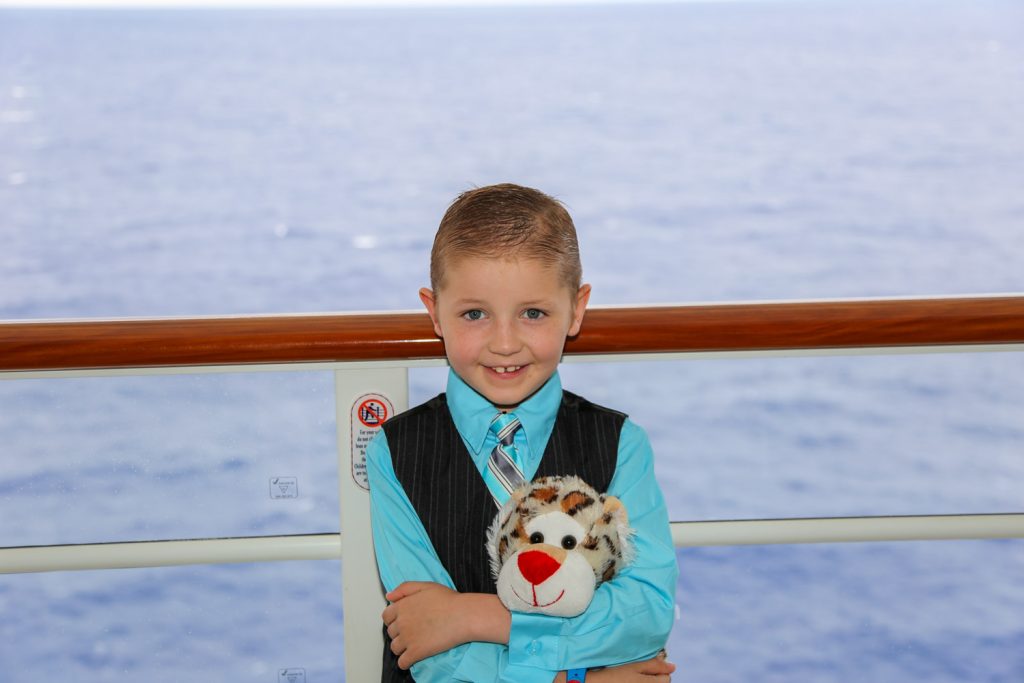 boy on cruise ship deck holding stuffed animal